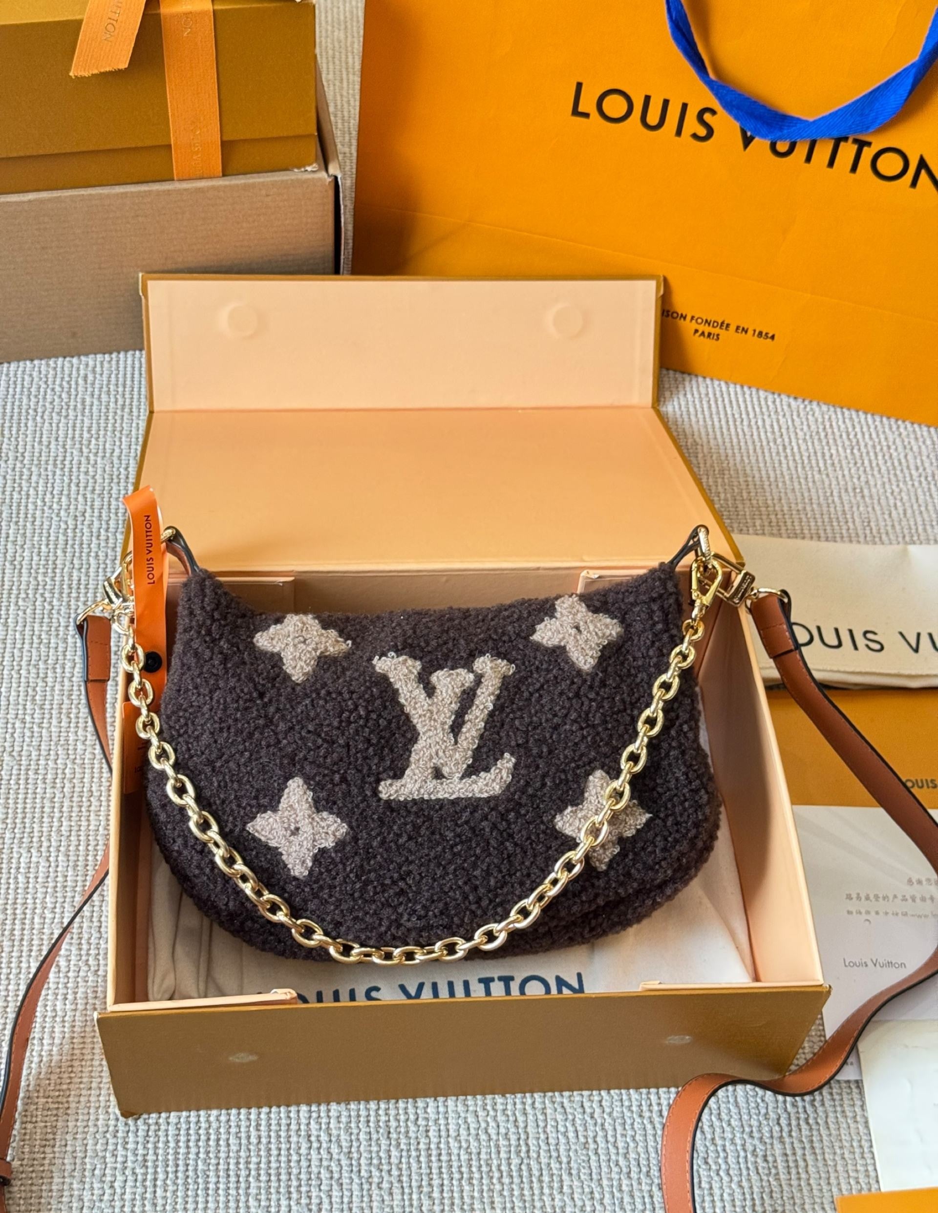 Louis Vuitton handbag with chain detail on a branded box