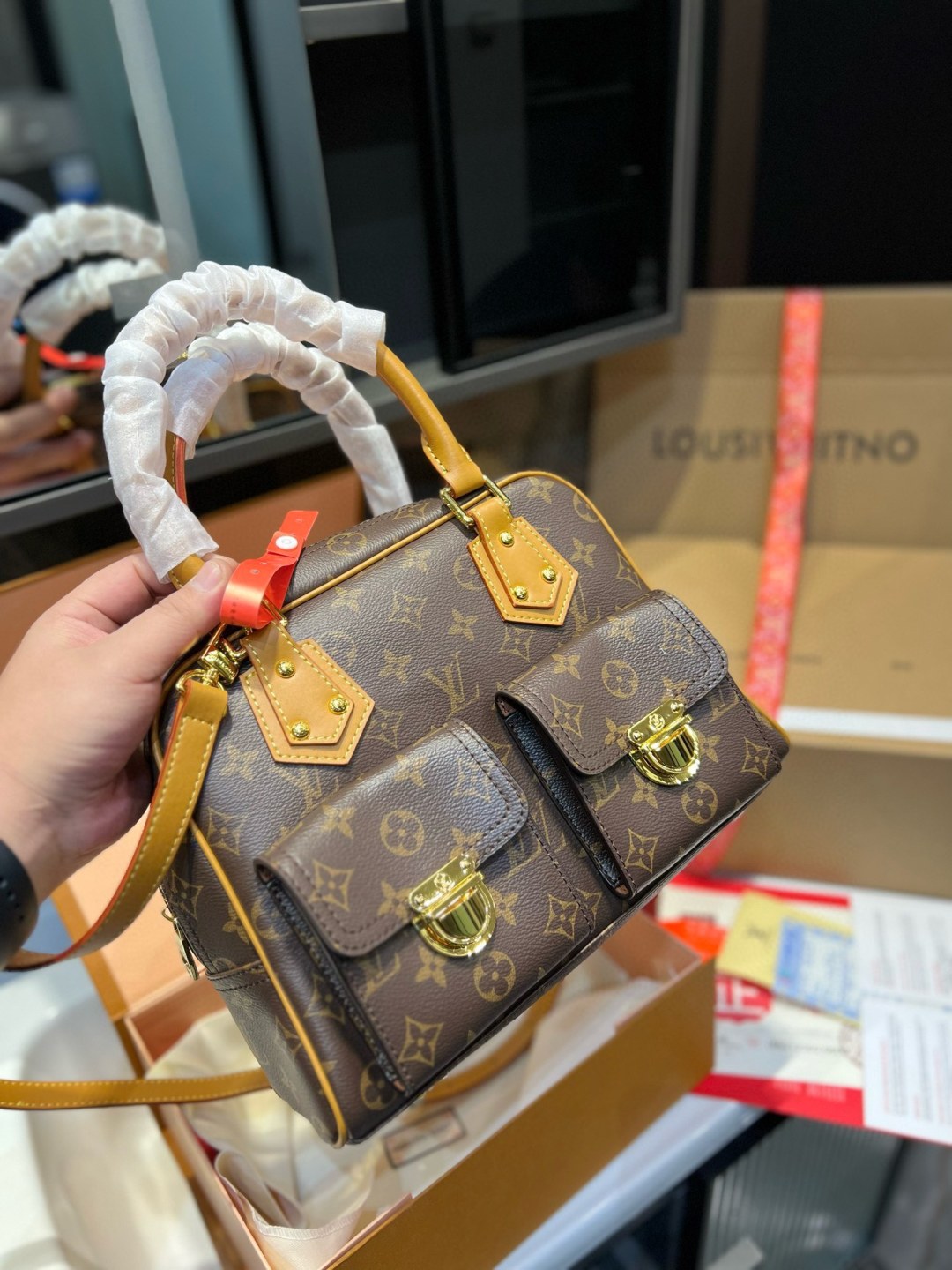 Louis Vuitton handbag with monogram pattern held by a person, with a blurred background.