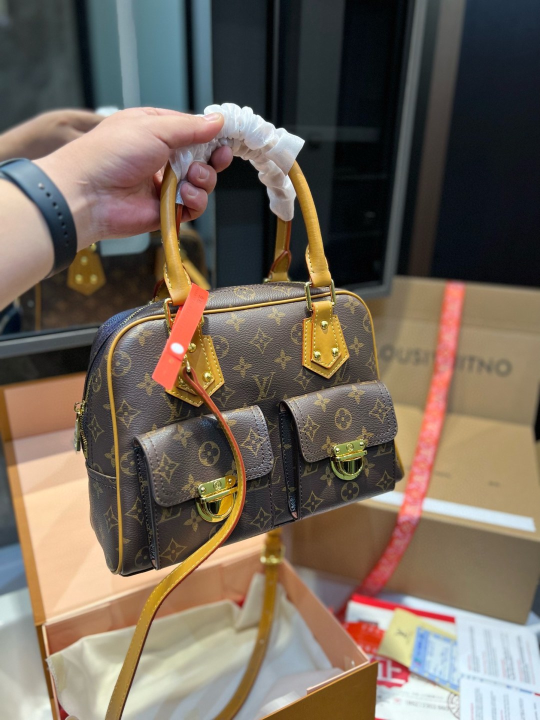 Louis Vuitton handbag with monogram pattern held by a person, with a blurred background.