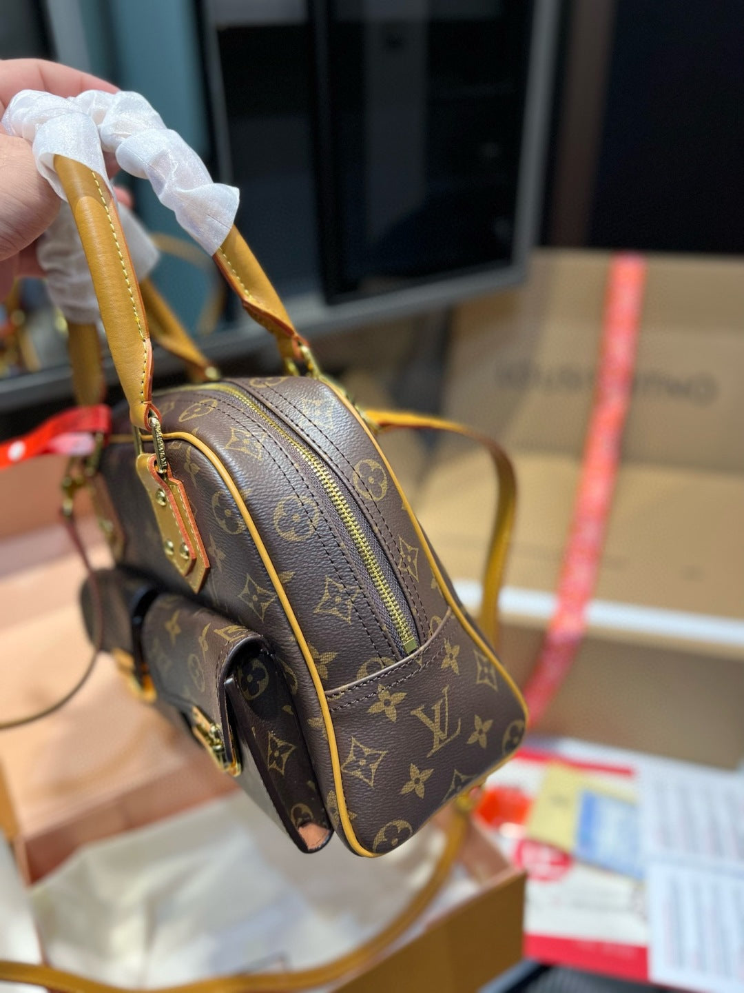 Louis Vuitton handbag with monogram pattern held by a person, with a blurred background.