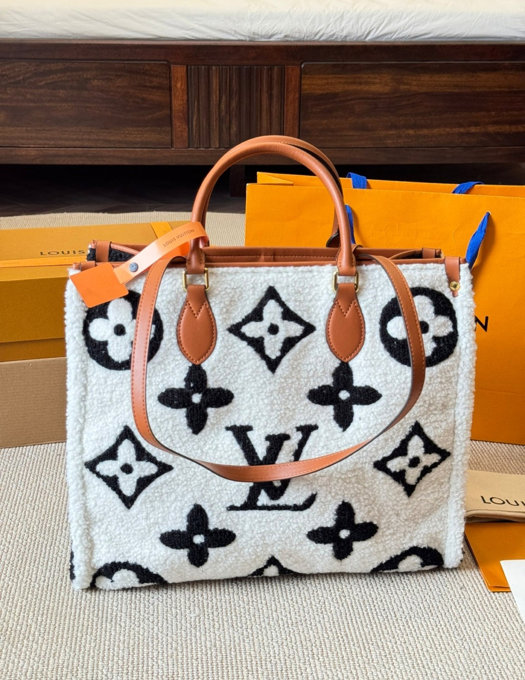 Designer handbag with monogram pattern on a surface with branded boxes in the background