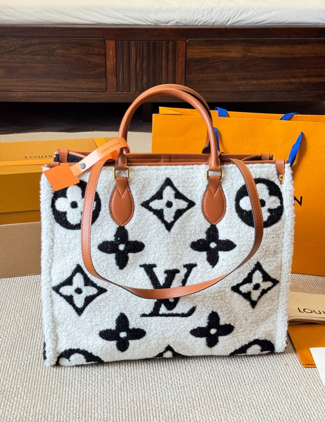 Designer handbag with monogram pattern on a surface with branded boxes in the background