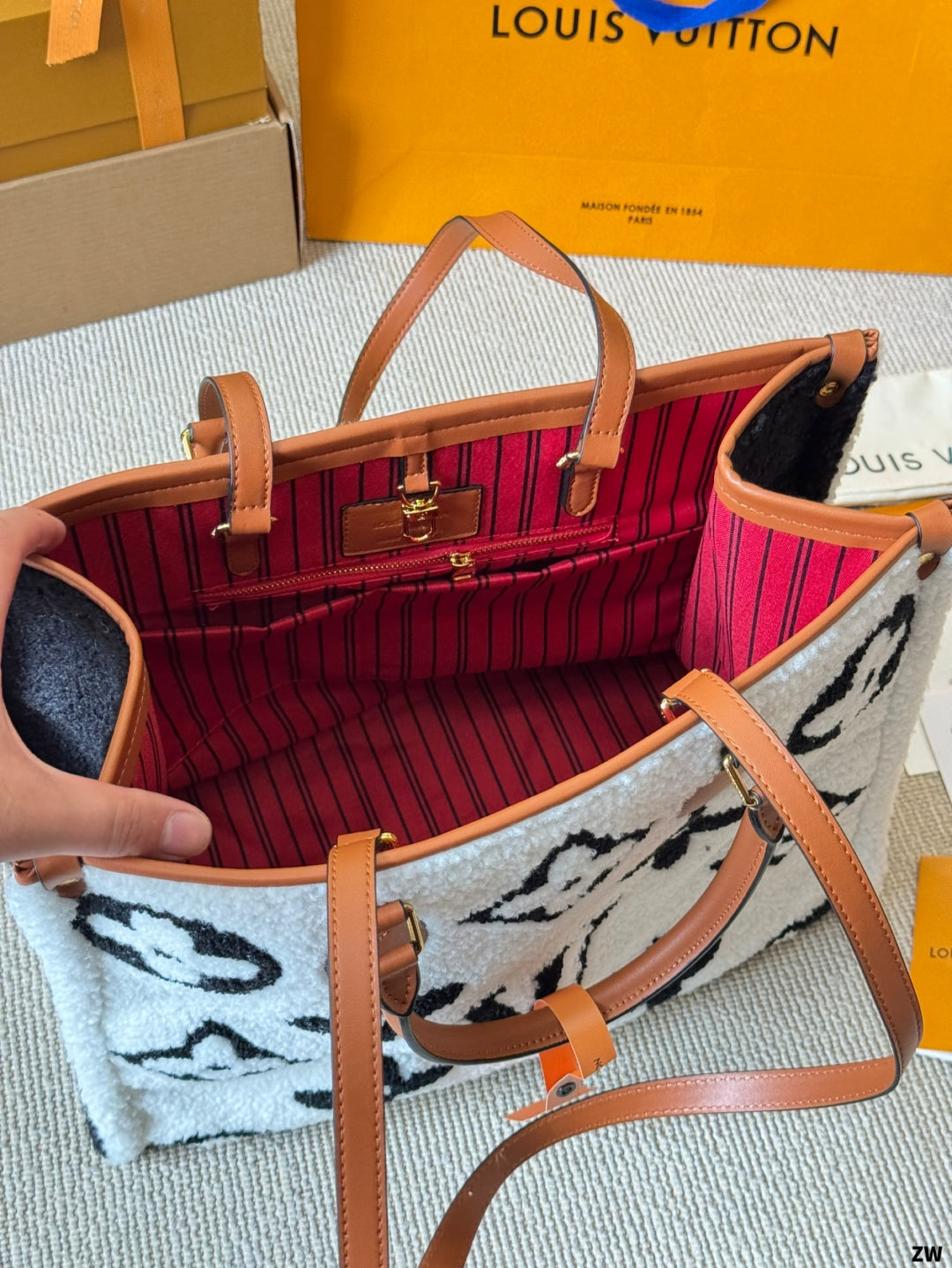 Louis Vuitton handbag with interior view, showing red lining and patterned interior, with a Louis Vuitton box in the background.