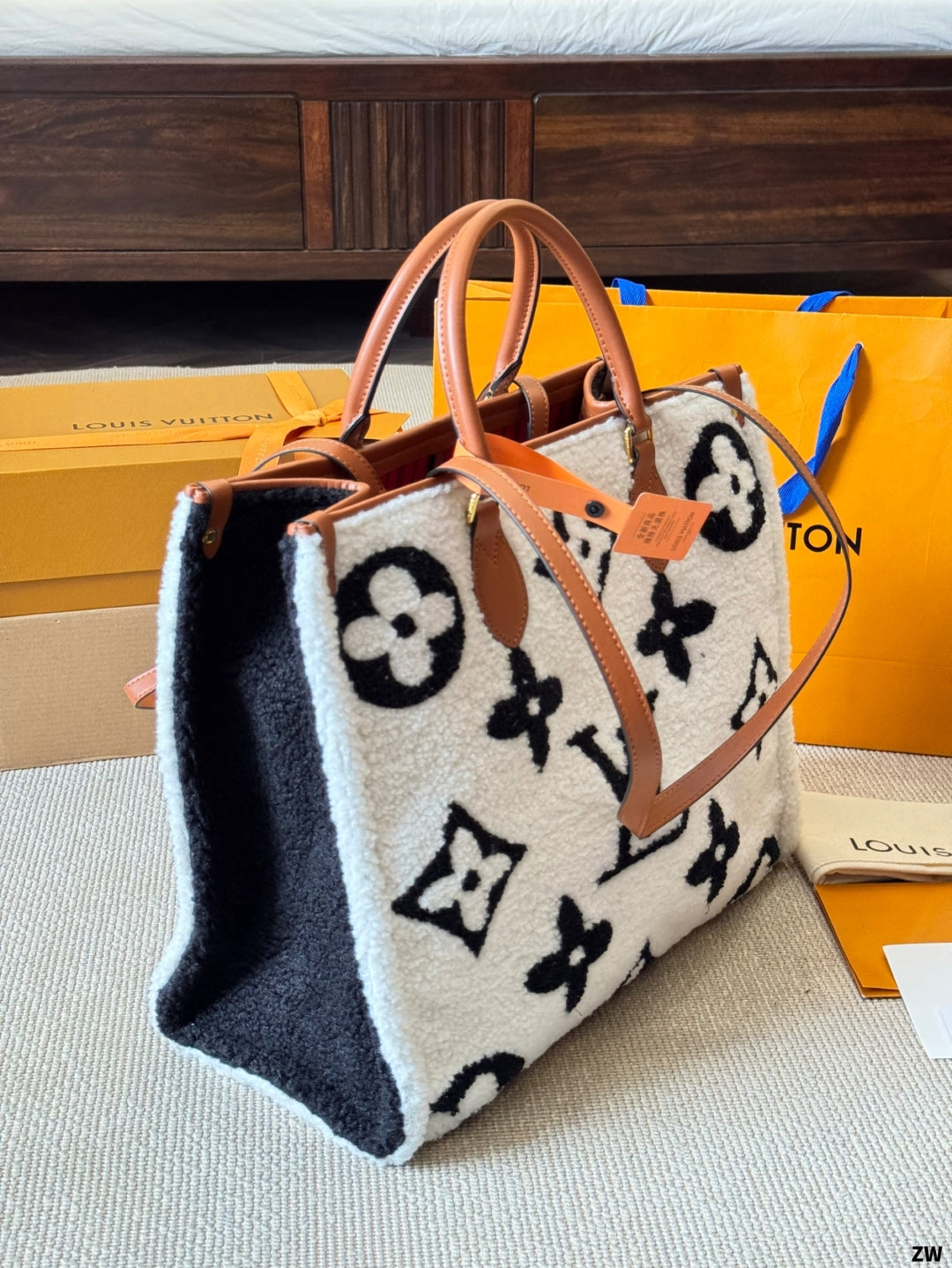 Designer handbag with monogram pattern on a surface with branded boxes in the background