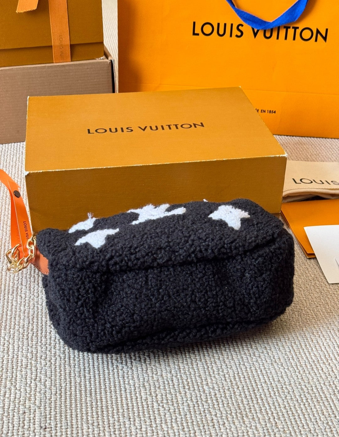Black pouch with white cloud patterns on a Louis Vuitton branded box.