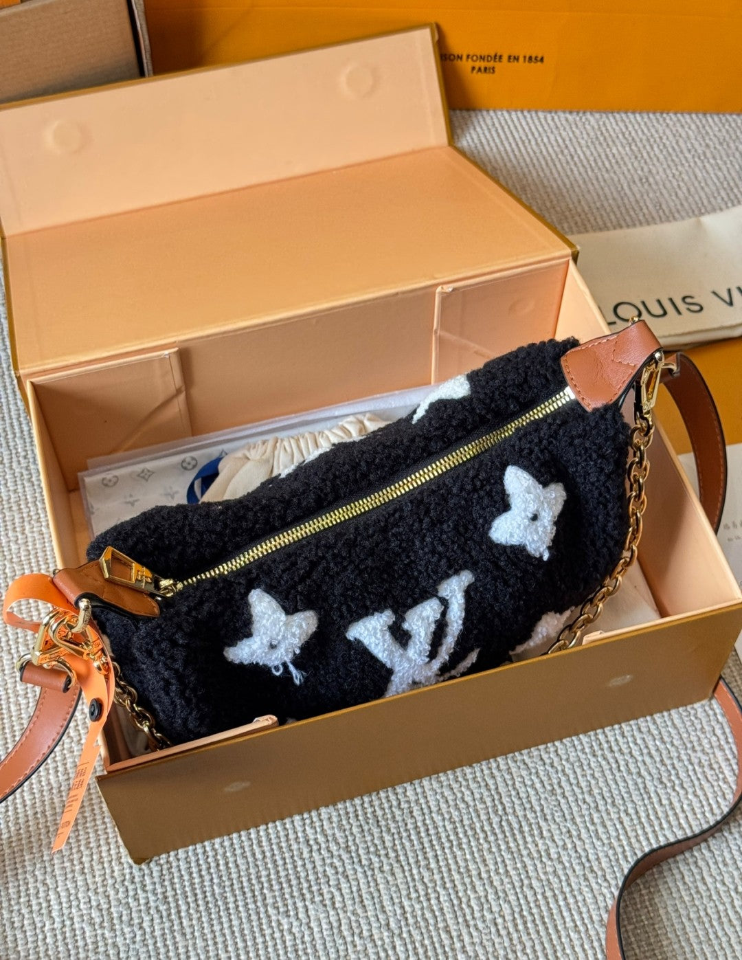 Black pouch with butterfly patterns in a Louis Vuitton box