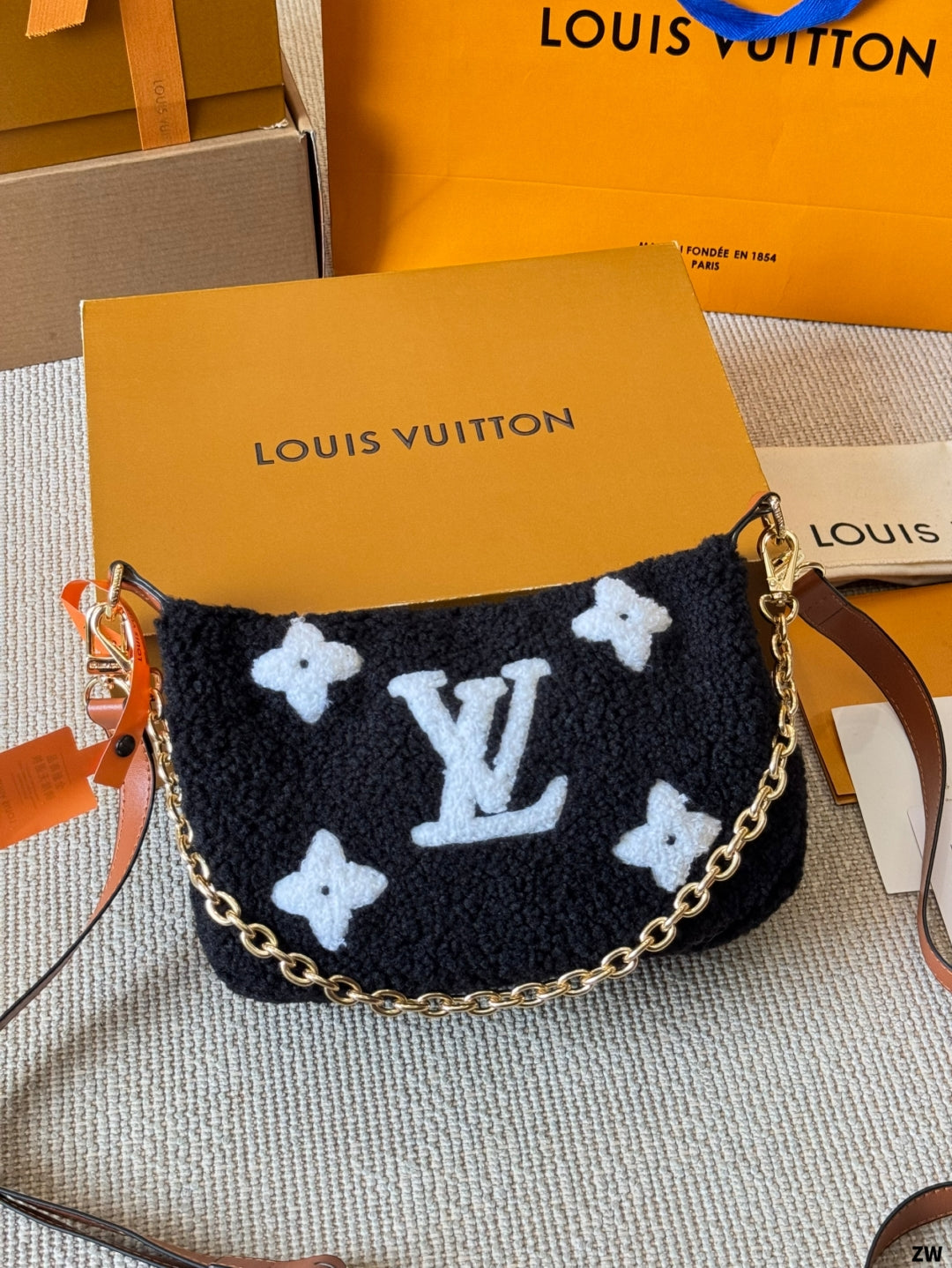 Louis Vuitton handbag with brand logo and packaging in the background