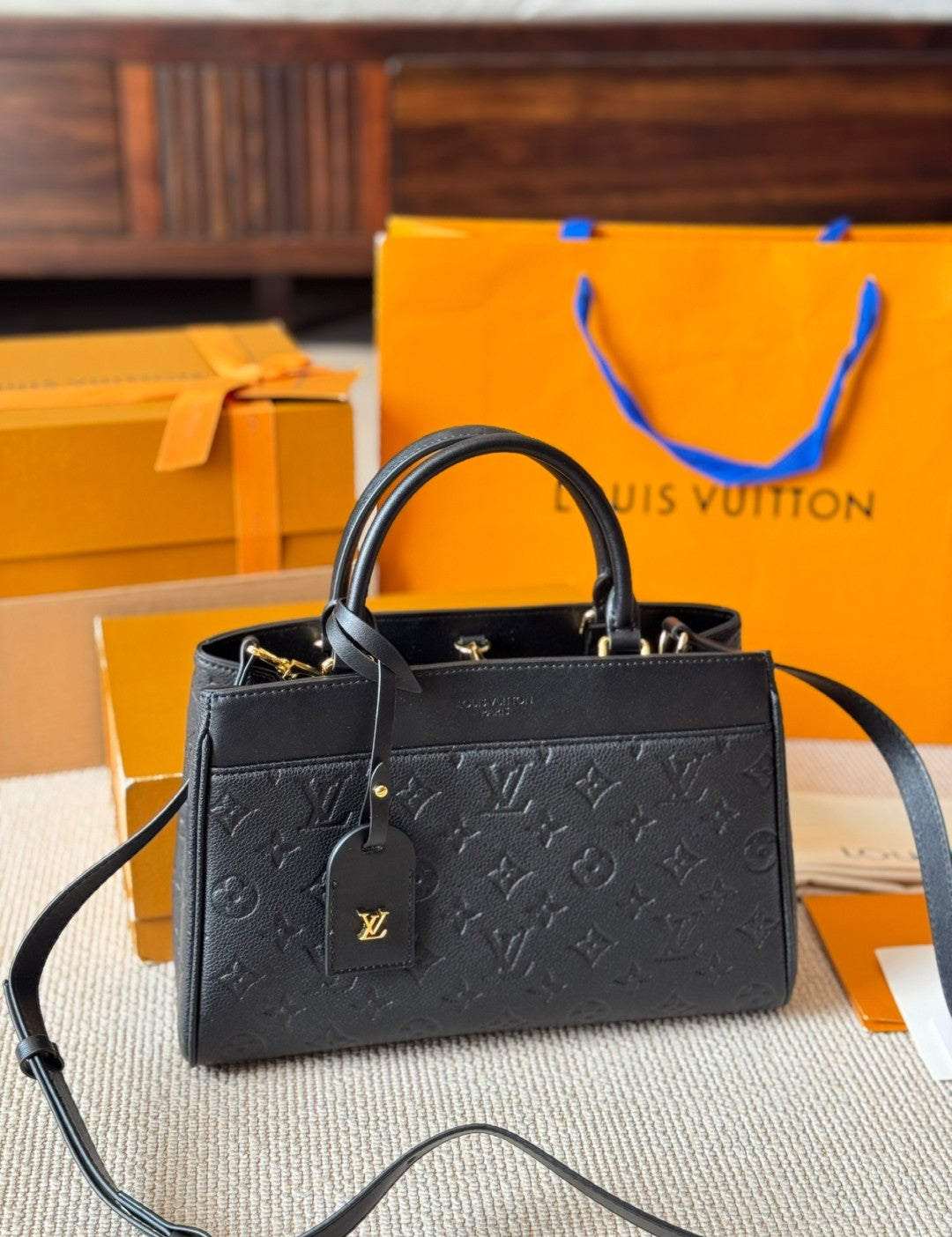 Black handbag with a brand tag on an orange Louis Vuitton background