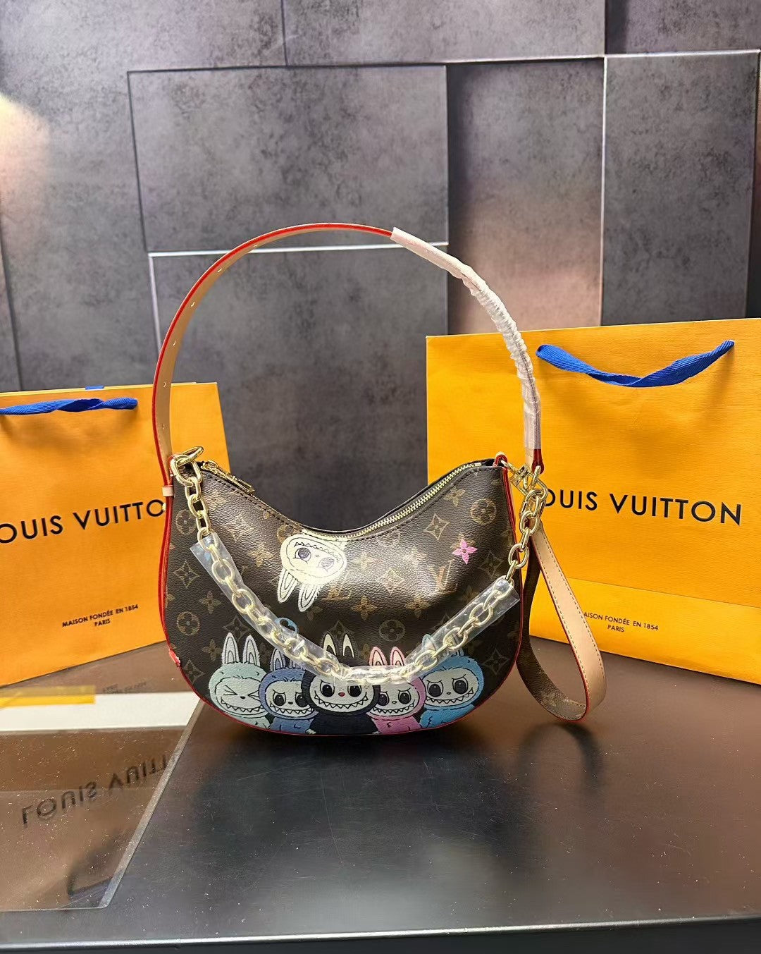 Louis Vuitton handbag with colorful designs on a dark surface with a Louis Vuitton bag in the background.