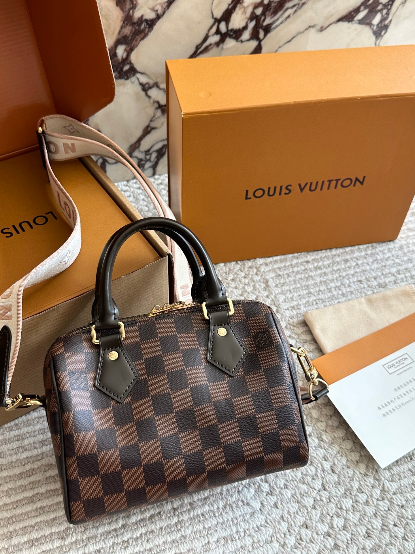 Louis Vuitton handbag with checkered pattern on a marble surface