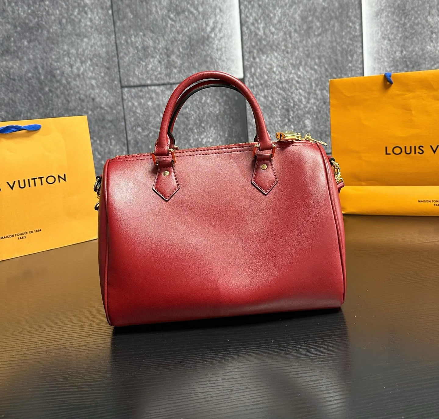 Red handbag with yellow Louis Vuitton bags in the background
