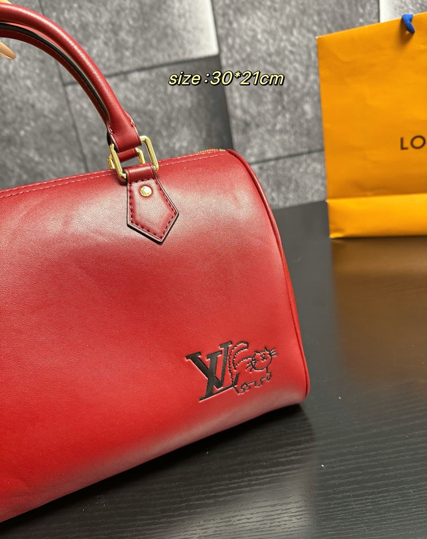 Red handbag with a visible brand logo on a dark surface, with a yellow tag in the background.
