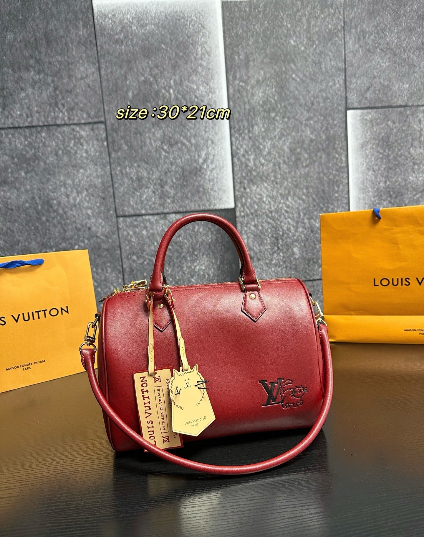 Red handbag with gold tag and 'Louis Vuitton' branding on a dark surface.